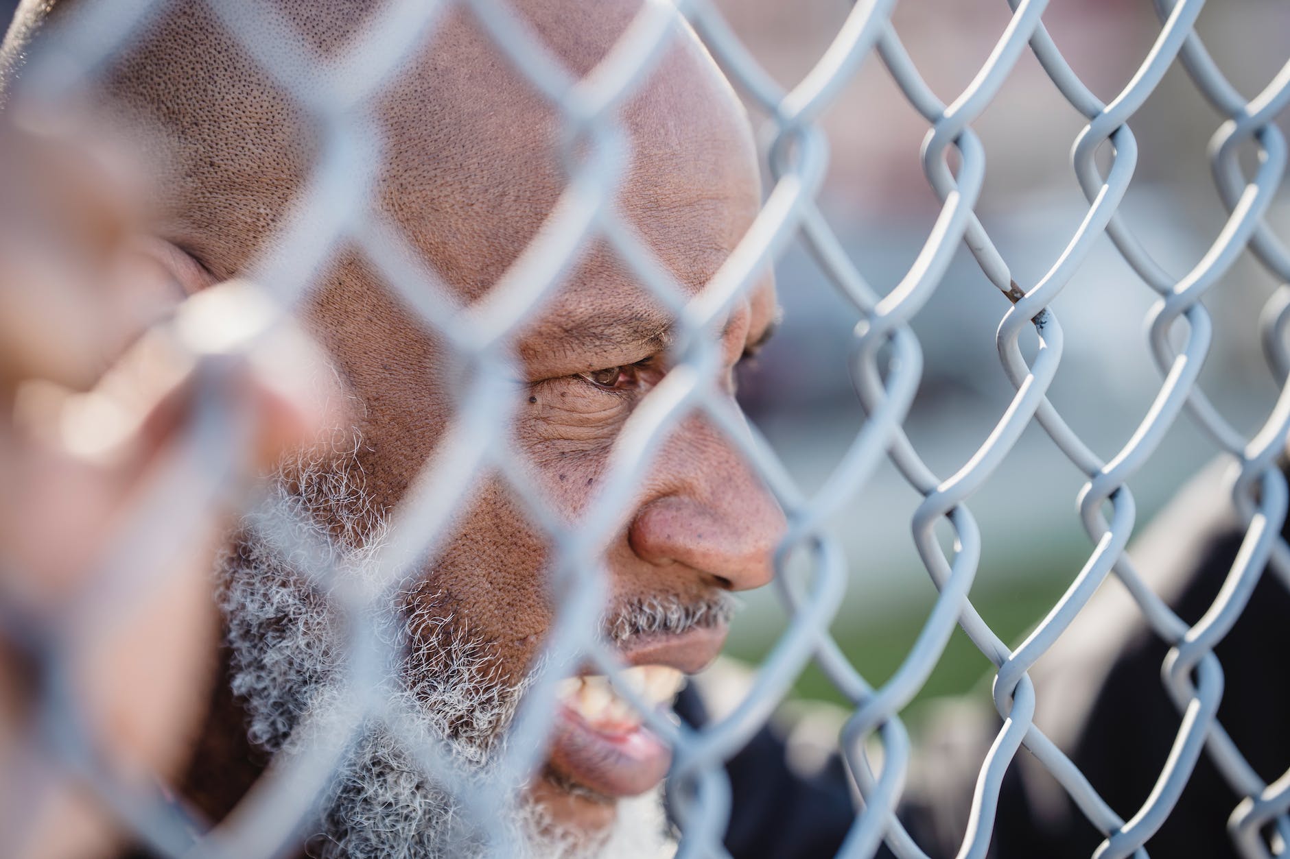 bearded man expressing anger behind net fence